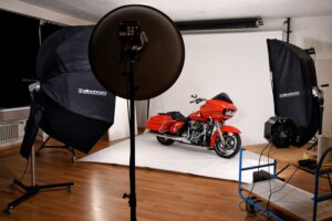 Grosser roter Töff steht auf Set im Fotostudio vor weissem Hintergrund vor Fotolampen
